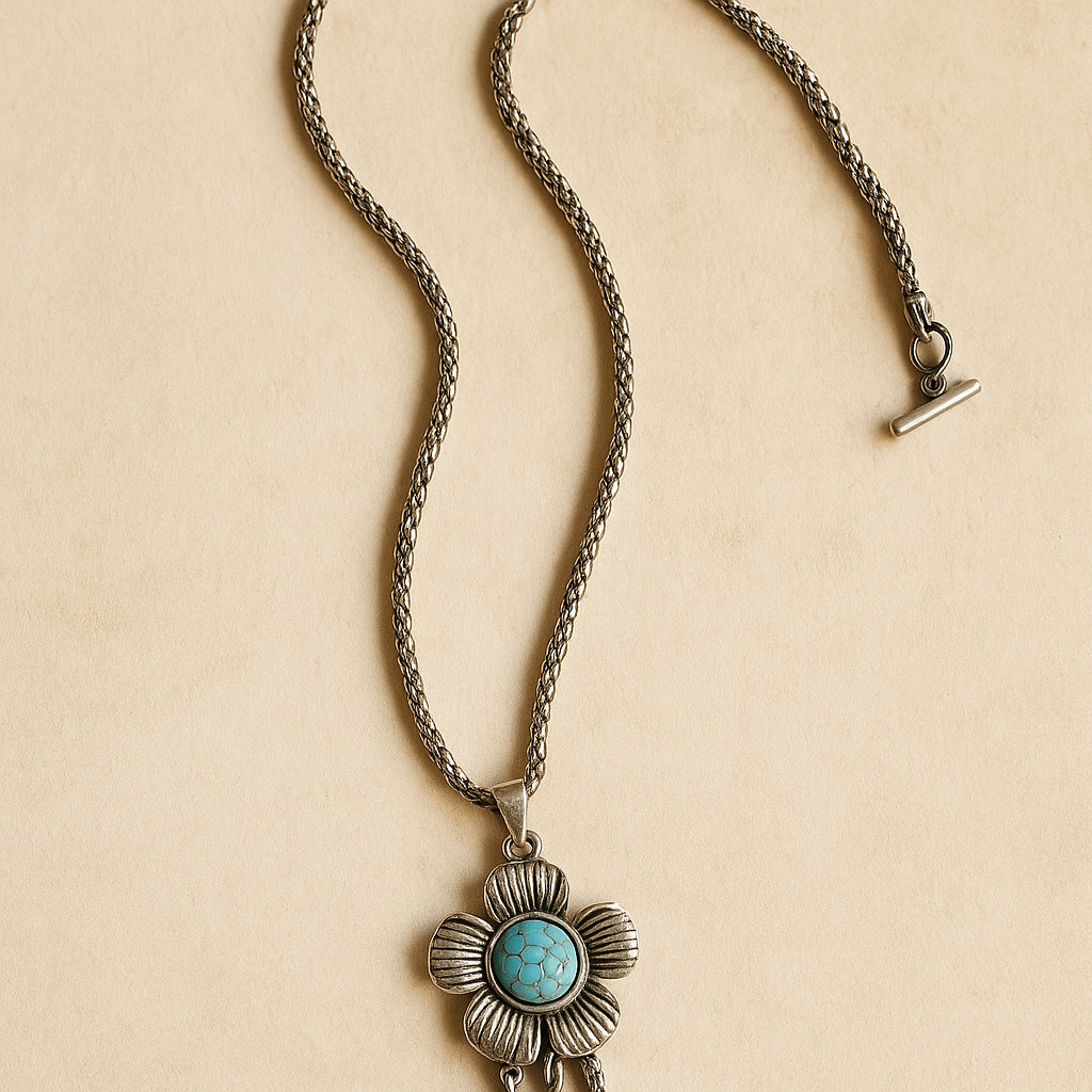 Zilverkleurige boho ketting met bloemvormige hanger en turquoise steen – handgemaakte bohemian ketting