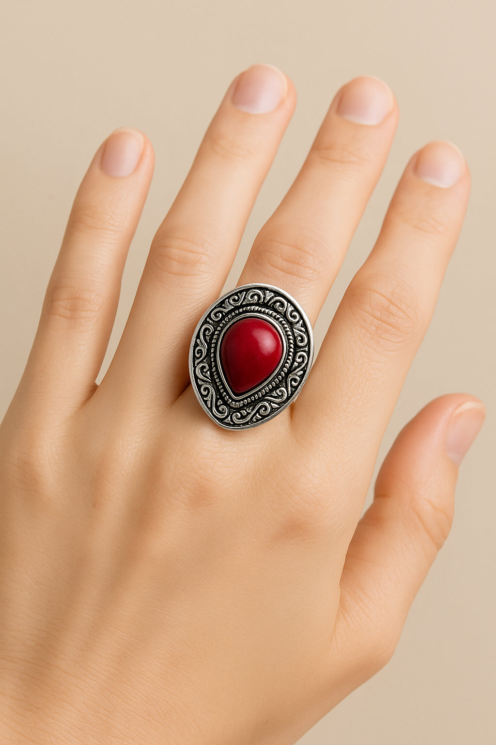Boho ring met rode druppelvormige steen en decoratieve zilverkleurige rand – gedragen aan de hand